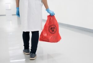 Scientist wearing blue gloves and red bag with bioharzard sign